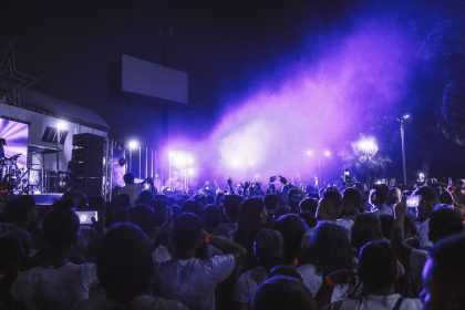 Grande público acompanha um show noturno diante de um palco iluminado com luzes coloridas.
