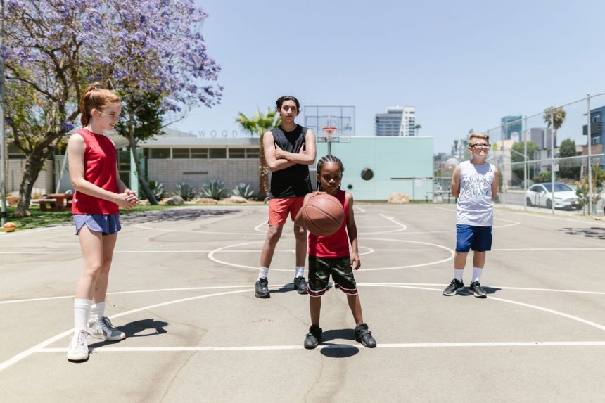 Grupo de crianças brinca e pratica esportes em uma quadra de basquete ao ar livre.
