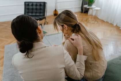 Duas mulheres sentadas em ambiente interno, conversando em um momento de apoio e empatia.